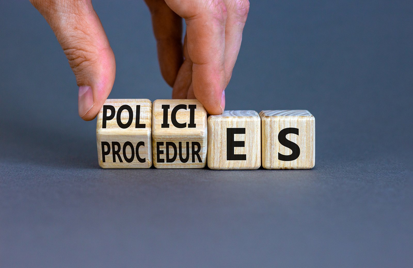 Policies vs procedures symbol. Businessman turns wooden cubes, changes the word procedures to policies. Beautiful grey table grey background, copy space. Business, policies, procedures concept.